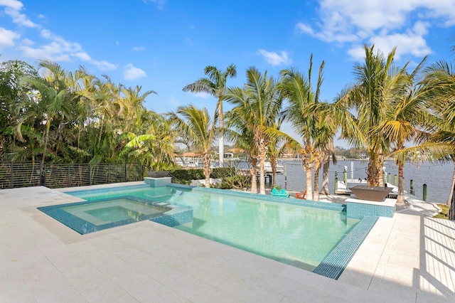 view of swimming pool featuring an in ground hot tub, a water view, and a patio