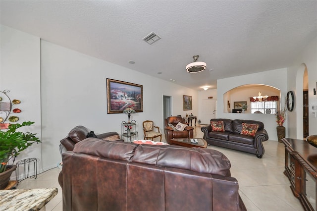 living room featuring light tile patterned flooring, a notable chandelier, and a textured ceiling