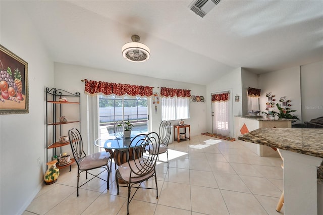 tiled dining room featuring vaulted ceiling