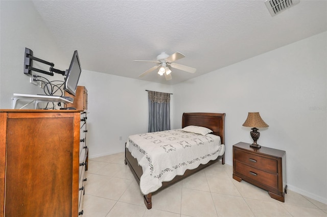 tiled bedroom with ceiling fan and a textured ceiling