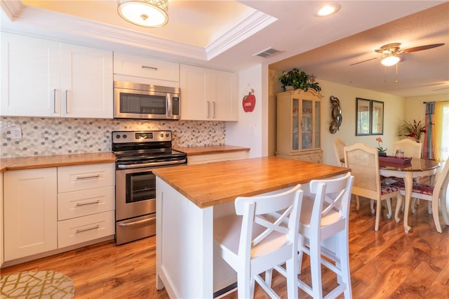 90 S Highland Ave Unit 1115, Tarpon Springs, FL 34689 - kitchen featuring butcher block countertops, stainless steel appliances, light wood-style floors, visible vents, and a tray ceiling