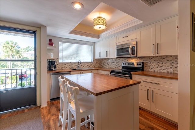 90 S Highland Ave Unit 1115, Tarpon Springs, FL 34689 - kitchen featuring butcher block countertops, stainless steel appliances, white cabinets, a sink, and a tray ceiling