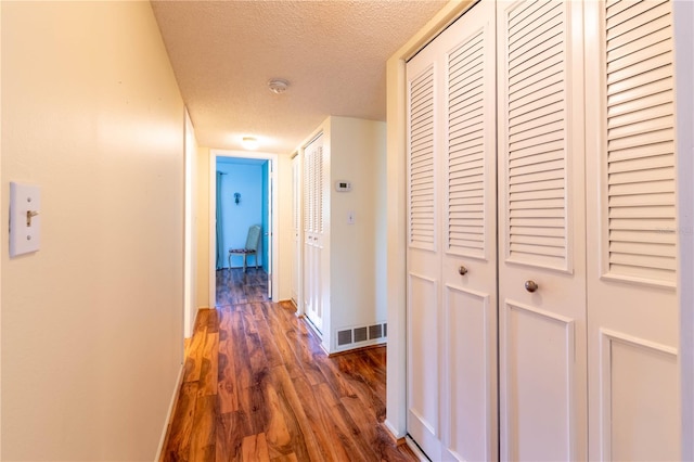 hall featuring a textured ceiling and dark wood-type flooring