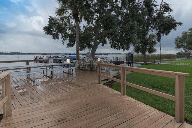 view of dock with a water view and a lawn