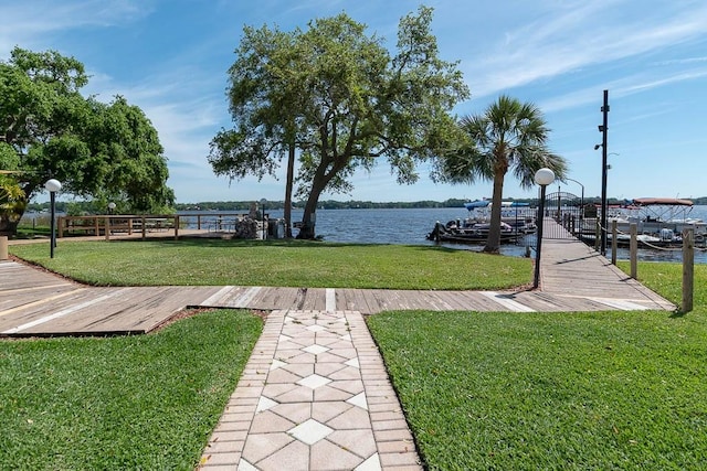 view of property's community with a water view, a boat dock, and a lawn