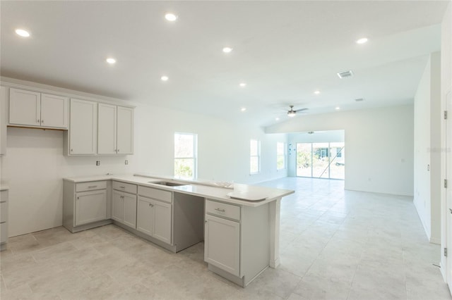 kitchen featuring kitchen peninsula, ceiling fan, sink, and lofted ceiling