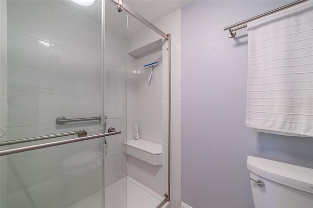 bathroom featuring a shower with shower door and toilet