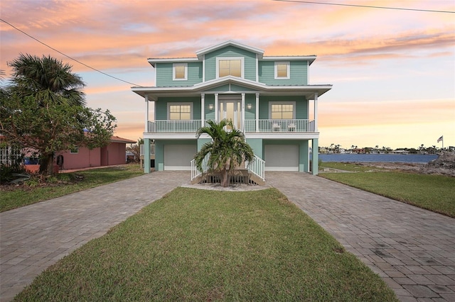 beach home featuring a porch, a garage, and a lawn