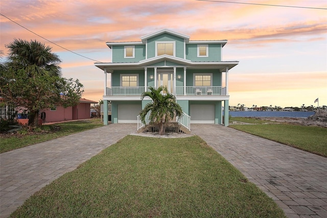 339 55th Ave, St Pete Beach, FL 33706 - coastal home featuring decorative driveway, a garage, a lawn, and a porch