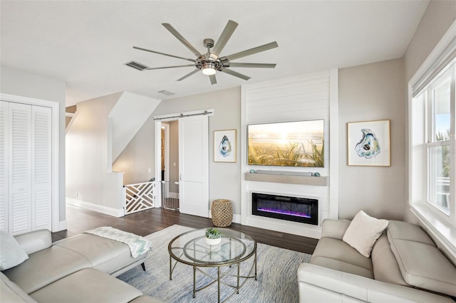 living room featuring a barn door, ceiling fan, and dark hardwood / wood-style flooring