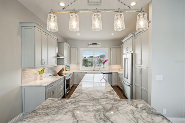 339 55th Ave, St Pete Beach, FL 33706 - kitchen with appliances with stainless steel finishes, a sink, light stone countertops, backsplash, and gray cabinetry