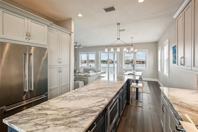 kitchen featuring dark hardwood / wood-style floors, stainless steel appliances, light stone counters, and a wealth of natural light