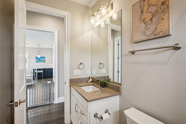 339 55th Ave, St Pete Beach, FL 33706 - half bathroom with vanity, toilet, baseboards, and wood finished floors