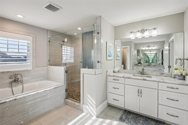 339 55th Ave, St Pete Beach, FL 33706 - bathroom with a bath, vanity, a shower stall, baseboards, and wood finished floors