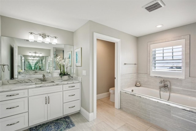 339 55th Ave, St Pete Beach, FL 33706 - bathroom featuring a garden tub, vanity, toilet, and baseboards