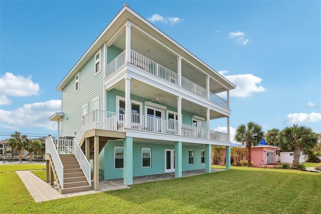 rear view of property with a patio, a yard, and a balcony