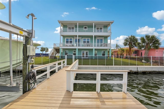 view of dock with a balcony, a yard, and a water view