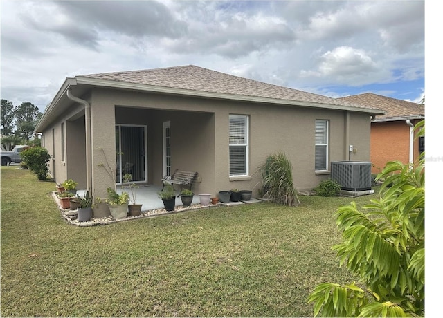 back of property with central air condition unit and a lawn