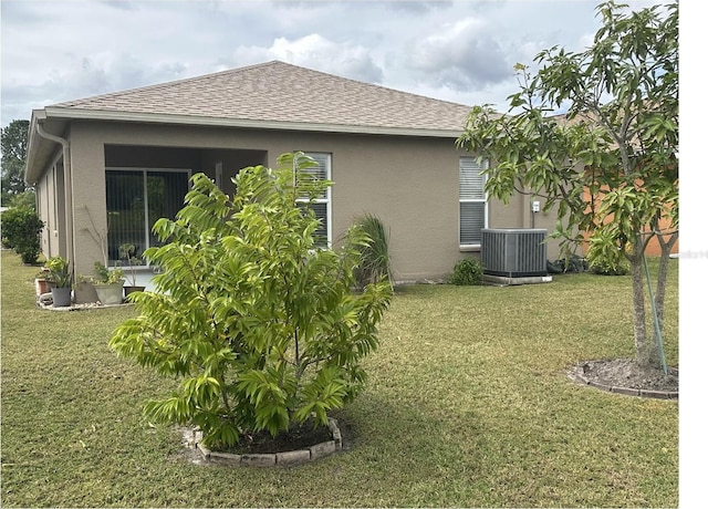 view of side of property with a lawn and central AC unit