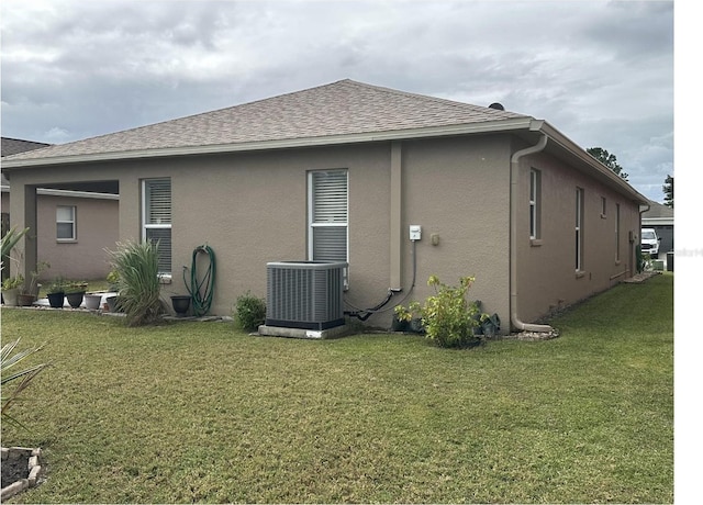 rear view of property featuring a lawn and central AC unit