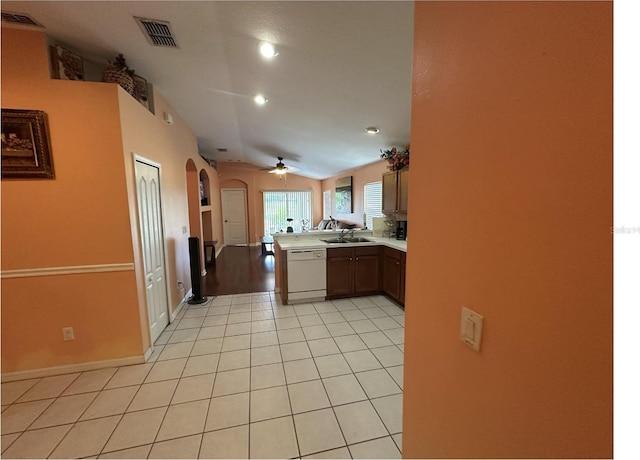 kitchen with sink, white dishwasher, kitchen peninsula, vaulted ceiling, and light tile patterned floors