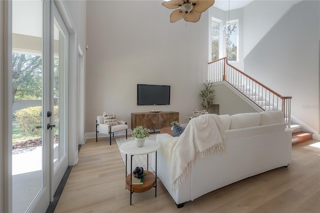 living room featuring light hardwood / wood-style floors, a healthy amount of sunlight, and a high ceiling