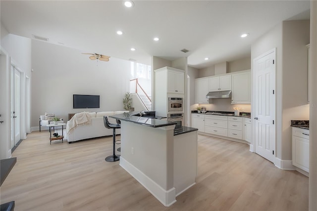 kitchen featuring a kitchen breakfast bar, appliances with stainless steel finishes, white cabinetry, light wood-type flooring, and sink