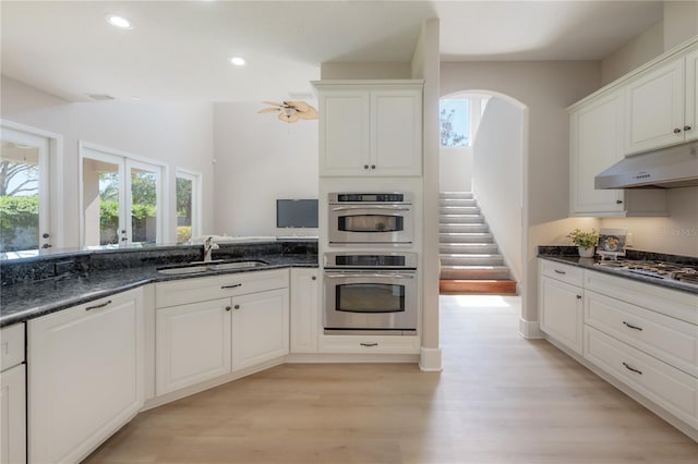 kitchen with sink, appliances with stainless steel finishes, light hardwood / wood-style flooring, and white cabinets