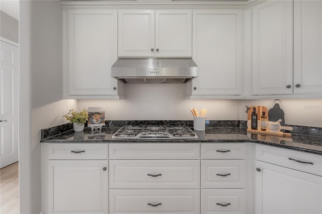 kitchen with stainless steel gas cooktop, wall chimney range hood, and white cabinets