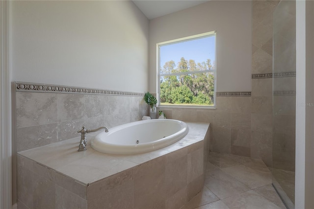 bathroom with tile walls, tile patterned flooring, and tiled tub