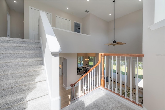 stairway with hardwood / wood-style flooring, a high ceiling, and ceiling fan