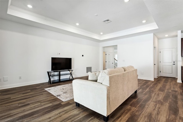 living room featuring crown molding, a tray ceiling, and dark hardwood / wood-style flooring