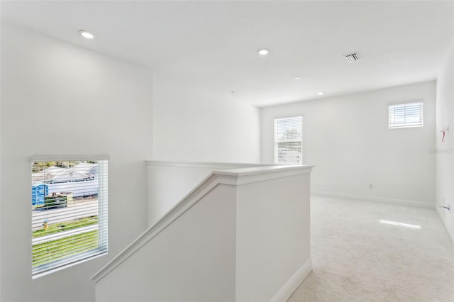 hall with light colored carpet and a wealth of natural light