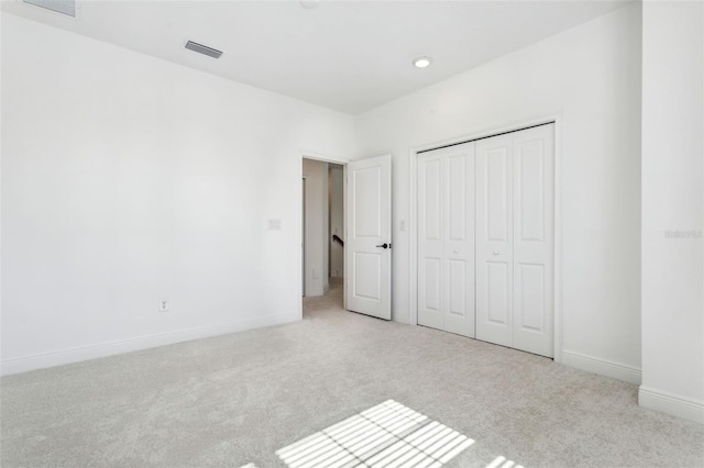 unfurnished bedroom with light carpet and a closet