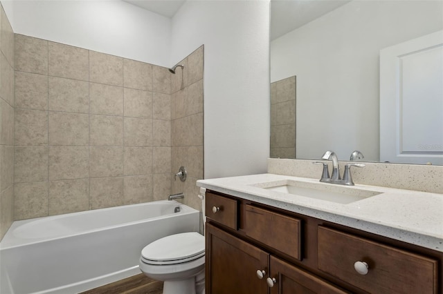 full bathroom with vanity, tiled shower / bath combo, hardwood / wood-style flooring, and toilet