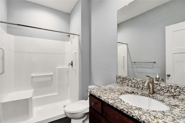 bathroom featuring toilet, a shower stall, and vanity