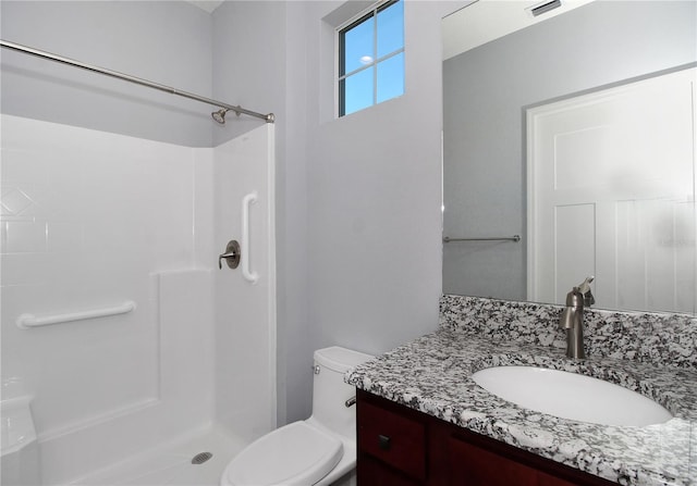 bathroom featuring toilet, vanity, and a shower