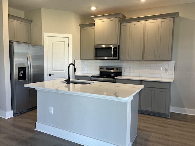 kitchen with sink, a center island with sink, gray cabinets, and appliances with stainless steel finishes