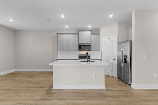 kitchen with an island with sink, appliances with stainless steel finishes, sink, and gray cabinetry