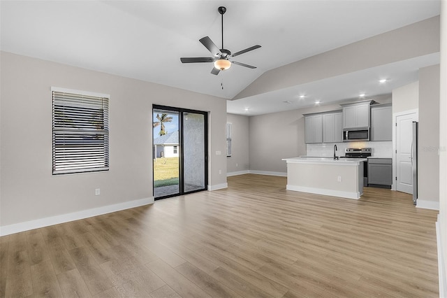 unfurnished living room featuring lofted ceiling, sink, light hardwood / wood-style flooring, and ceiling fan