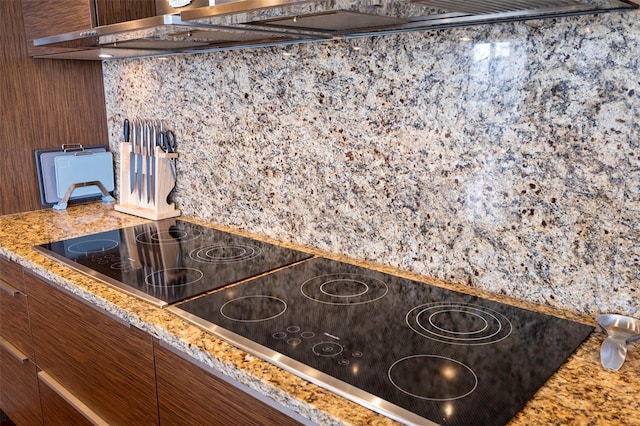 details with black electric stovetop and light stone counters