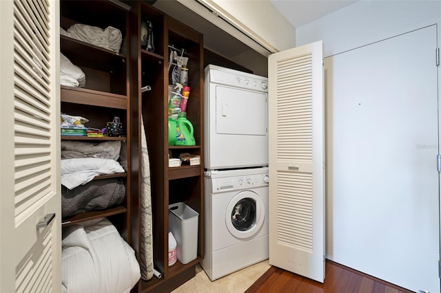 washroom with hardwood / wood-style floors and stacked washer / dryer