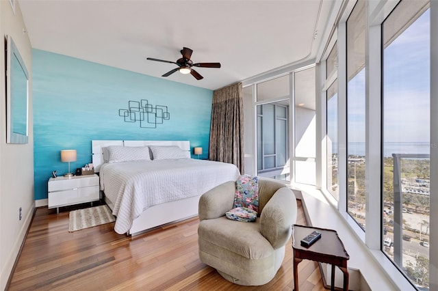 bedroom with ceiling fan, multiple windows, and hardwood / wood-style floors