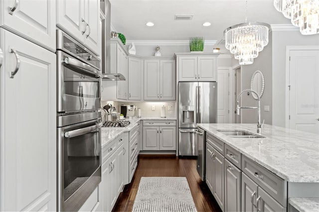 kitchen featuring a center island with sink, sink, pendant lighting, crown molding, and stainless steel appliances