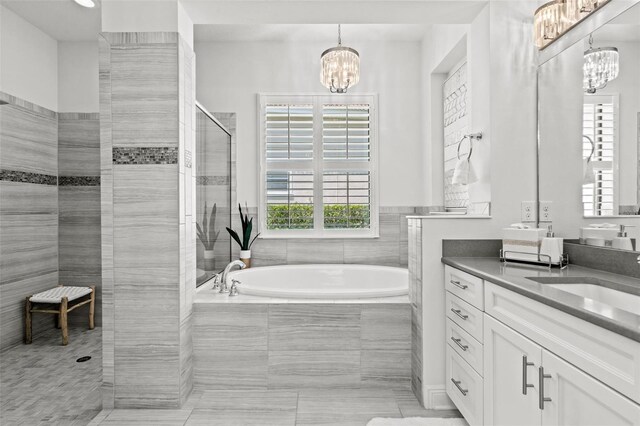 bathroom featuring vanity, an inviting chandelier, tile patterned flooring, and plus walk in shower