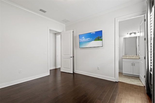 unfurnished bedroom with connected bathroom, dark wood-type flooring, ornamental molding, and sink