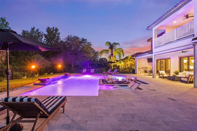 pool at dusk featuring a jacuzzi, ceiling fan, pool water feature, a patio area, and outdoor lounge area