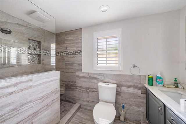 bathroom featuring tile walls, vanity, toilet, and tiled shower