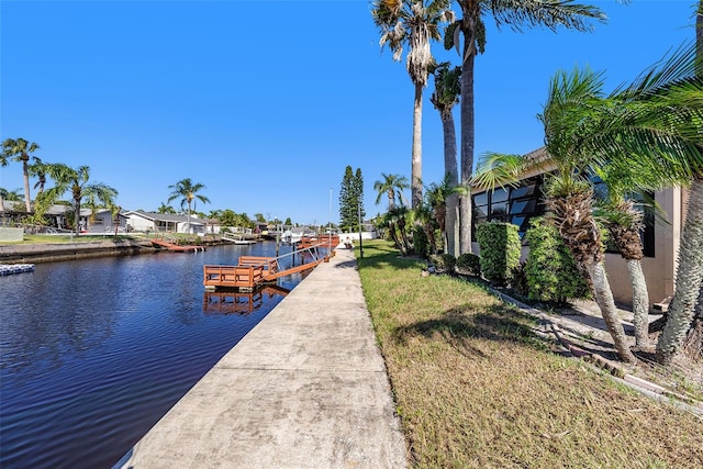 view of dock with a water view and a lawn