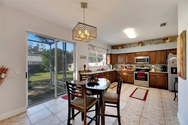 kitchen with appliances with stainless steel finishes, sink, hanging light fixtures, a notable chandelier, and decorative backsplash